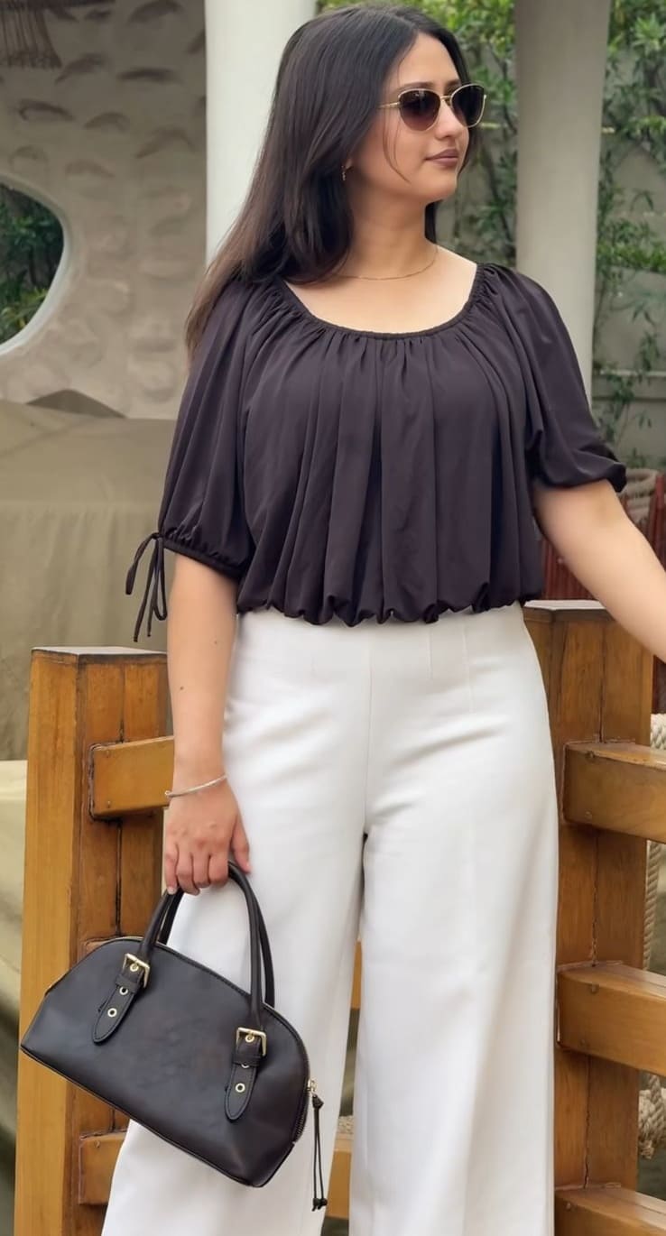 Charcoal puff-sleeve top with white wide-leg trousers and a black structured handbag