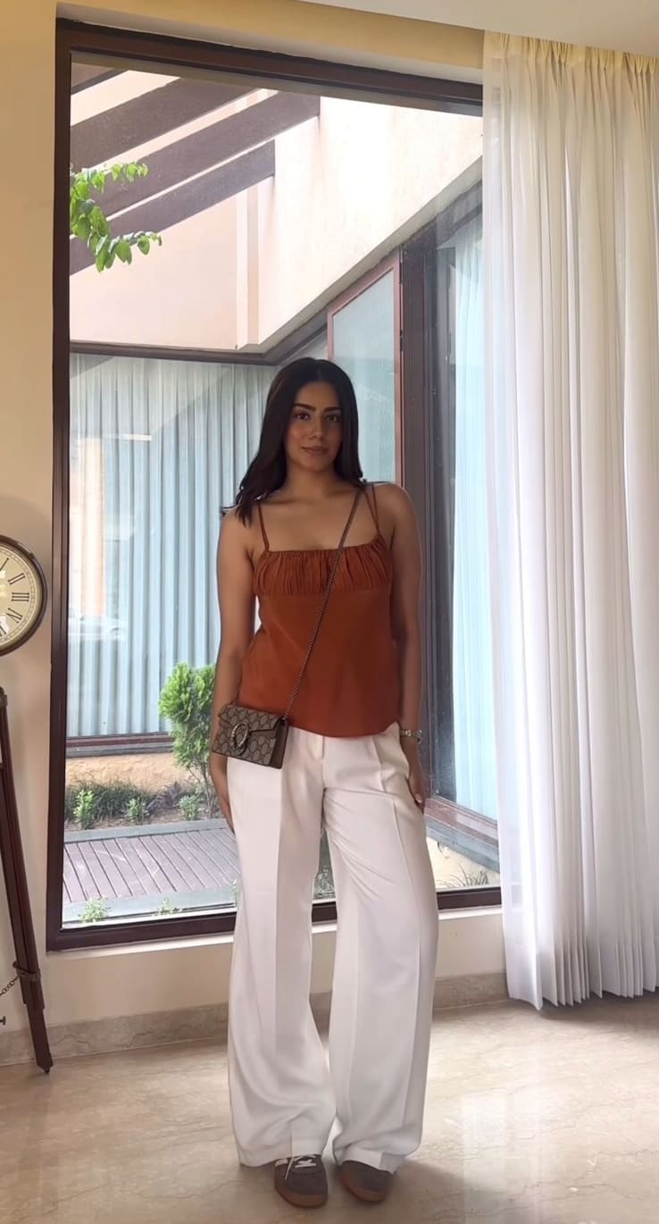 Rust orange cami top with white wide-leg trousers and a small printed crossbody bag
